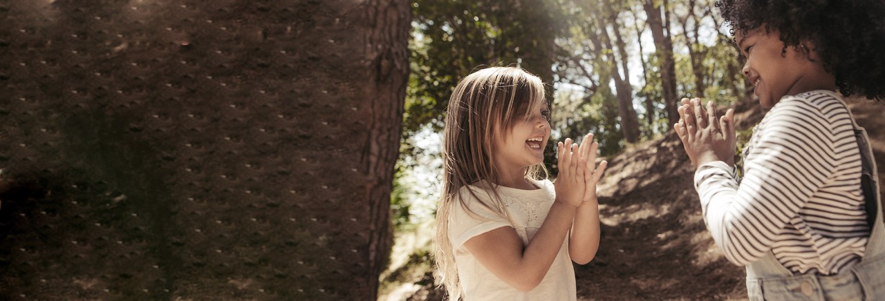 Två barn spelar klappspel  i skogen.